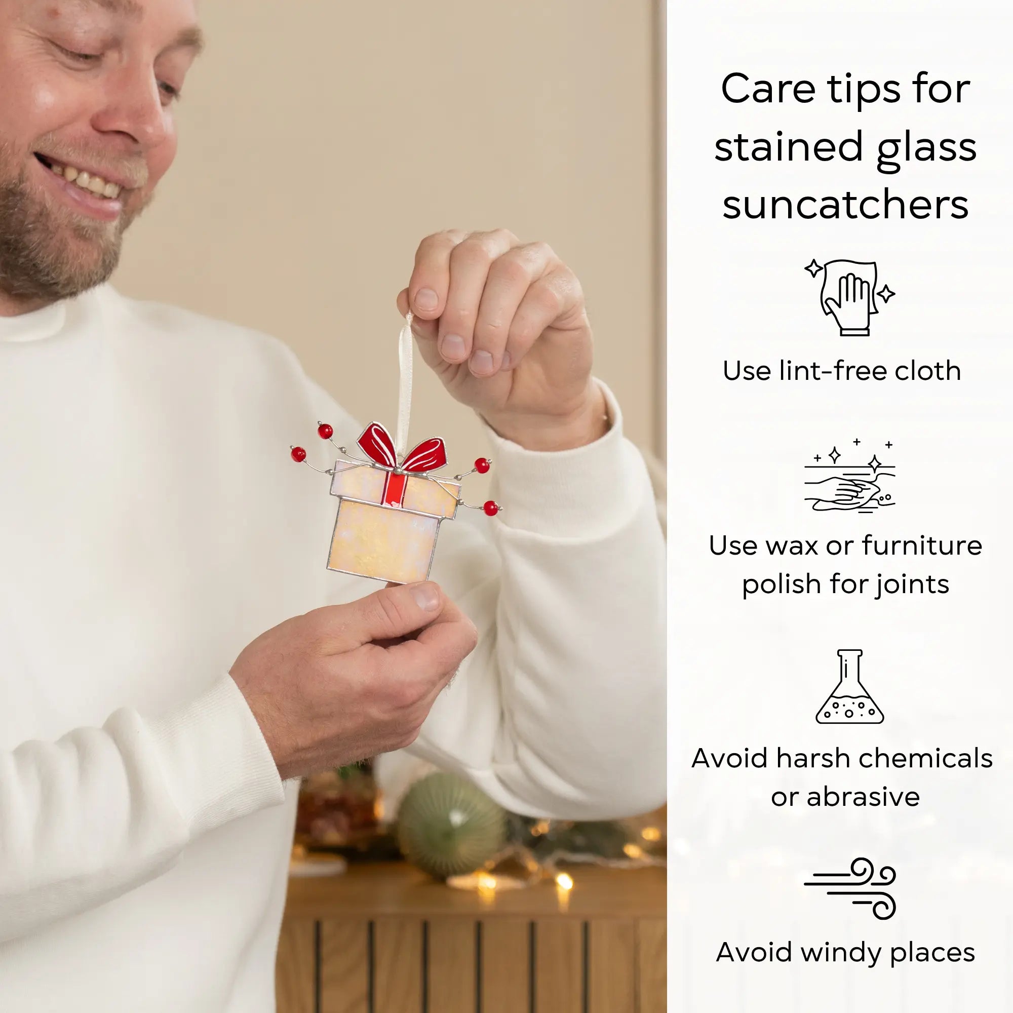 Person holding stained glass gift box ornament with red ribbon with care tips beside: use lint-free cloth, polish joints with car wax or furniture polish, avoid harsh chemicals, and windy places.