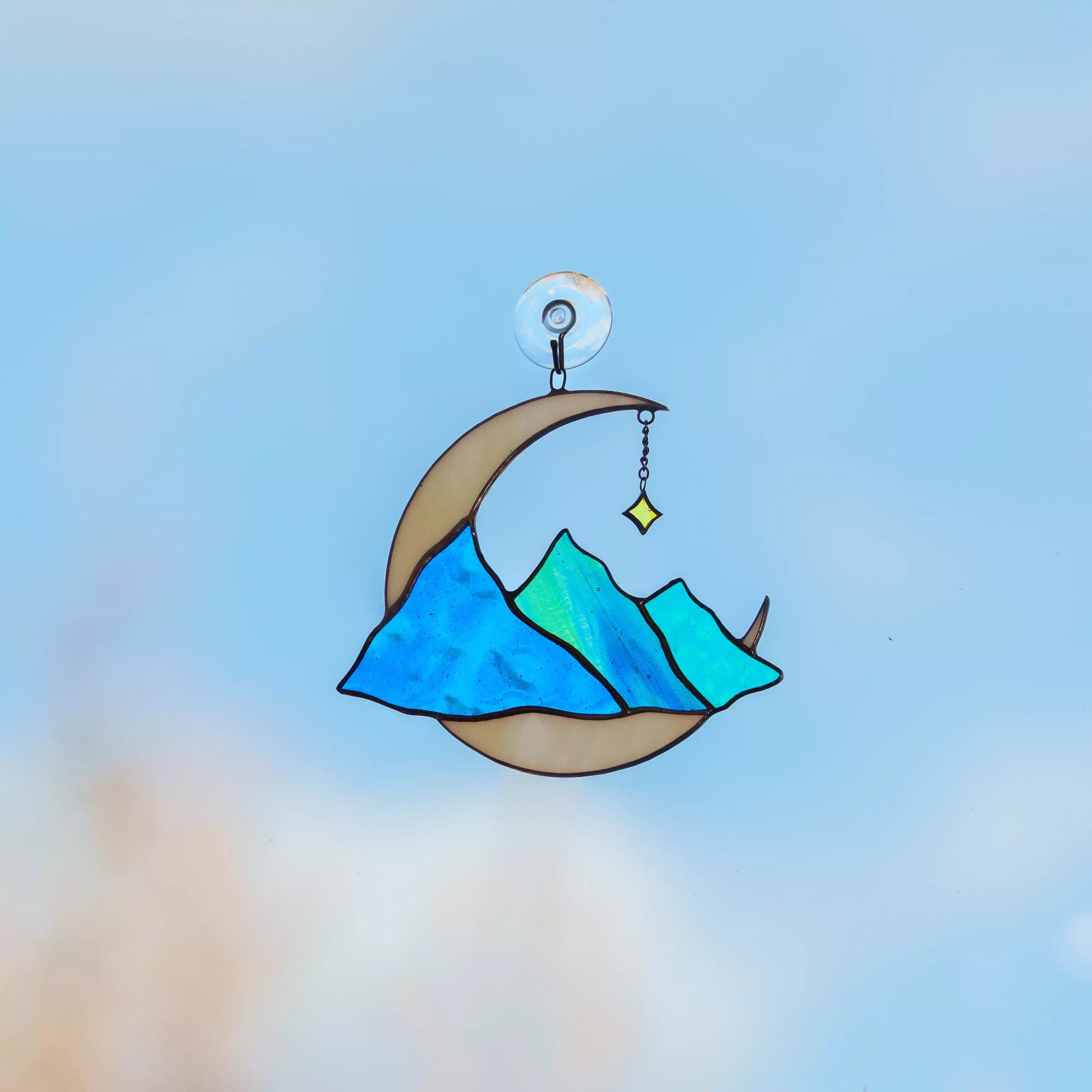 Stained glass celestial suncatcher crescent moon with blue mountains hanging on a window