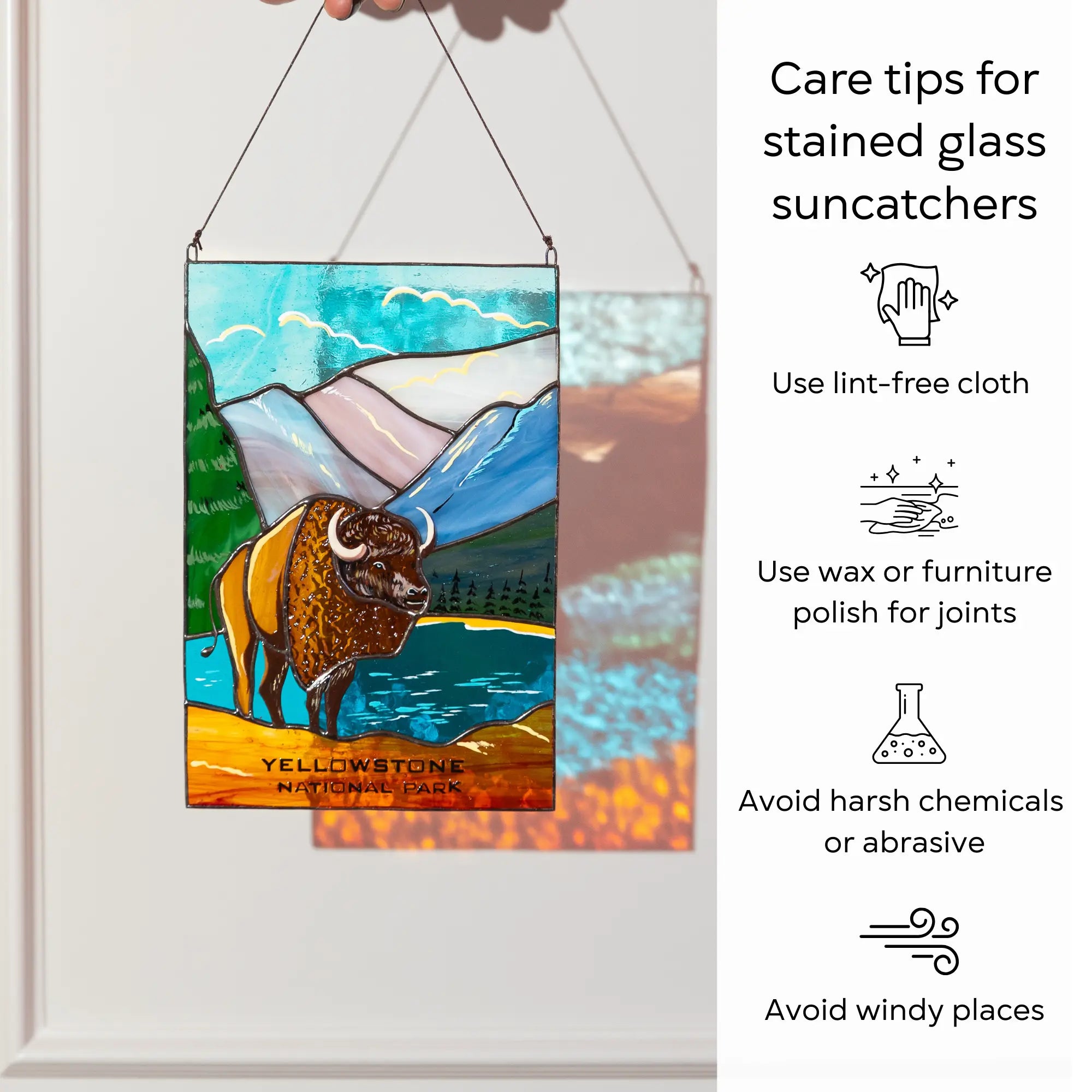 A hand holding the Yellowstone stained glass panel next to care tips for cleaning and maintaining suncatchers: use lint-free cloth, polish joints with car wax or furniture polish, avoid harsh chemicals, and windy places.