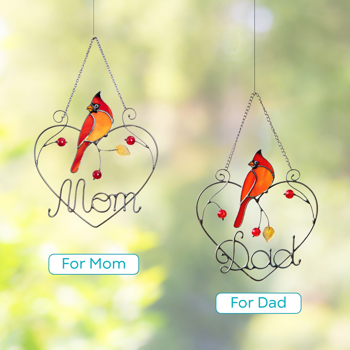 Two cardinal bird suncatchers with words “Mom” and “Dad” in metal hearts, shown outdoors.