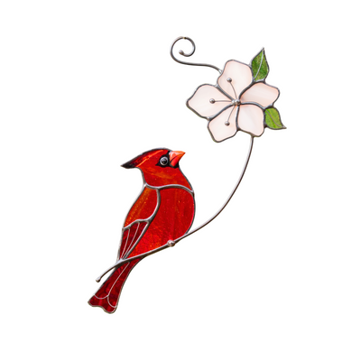 Deep red cardinal with pink flower on a curved branch.