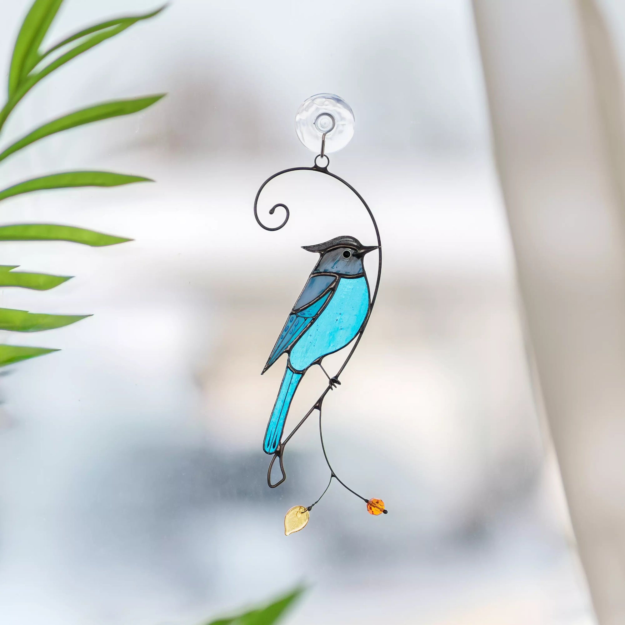Steller jay bird stained glass suncatcher hanging on a window