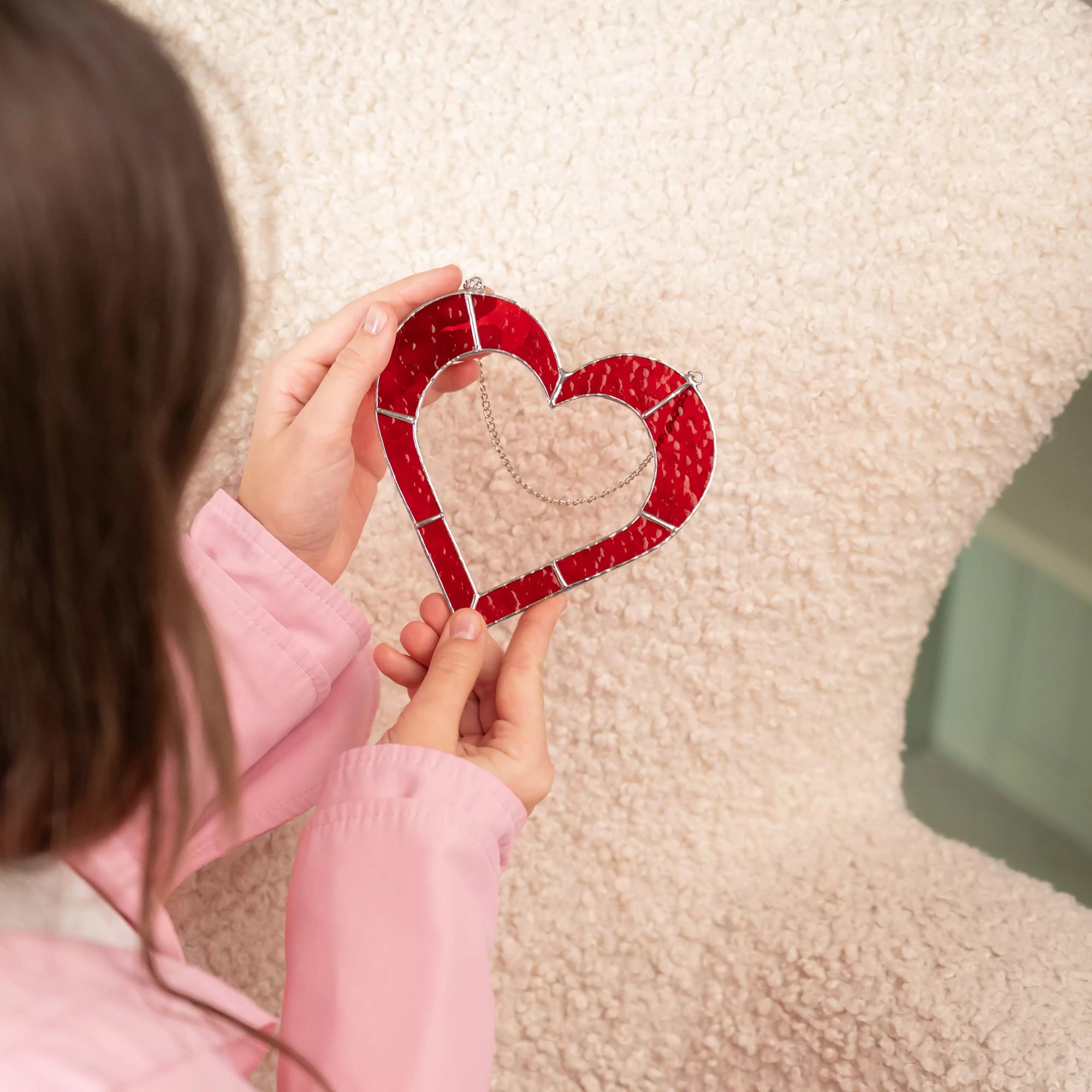 Close-up view of a red stained glass heart suncatcher showing textured glass and solder details.