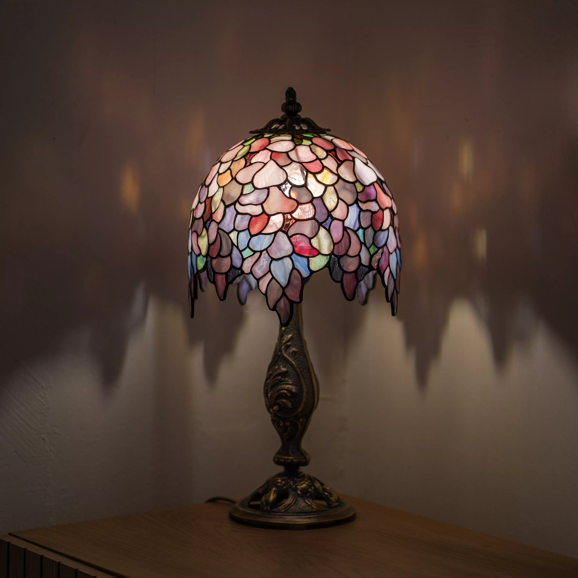 Tiffany table lamp Wisteria with a colorful glass shade on a wooden surface.