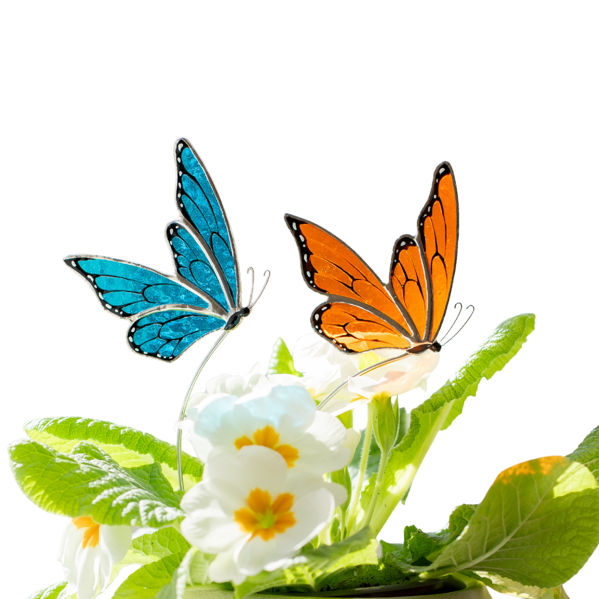 Two stained glass butterfly plant stakes, one blue and one orange, on a white background with green leaves and flowers.