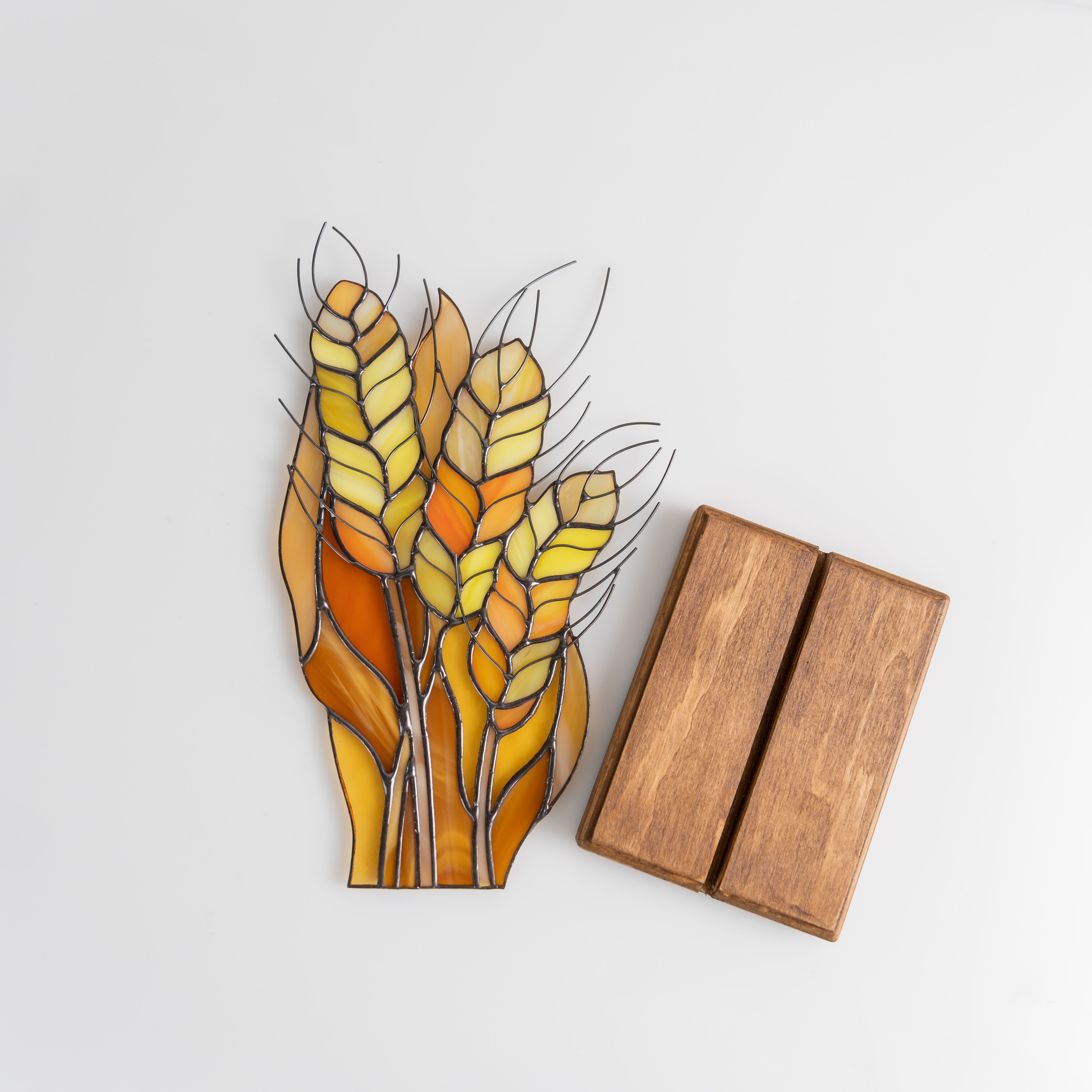 Stained glass wheat bundle with separate wooden base pieces placed on a white background.