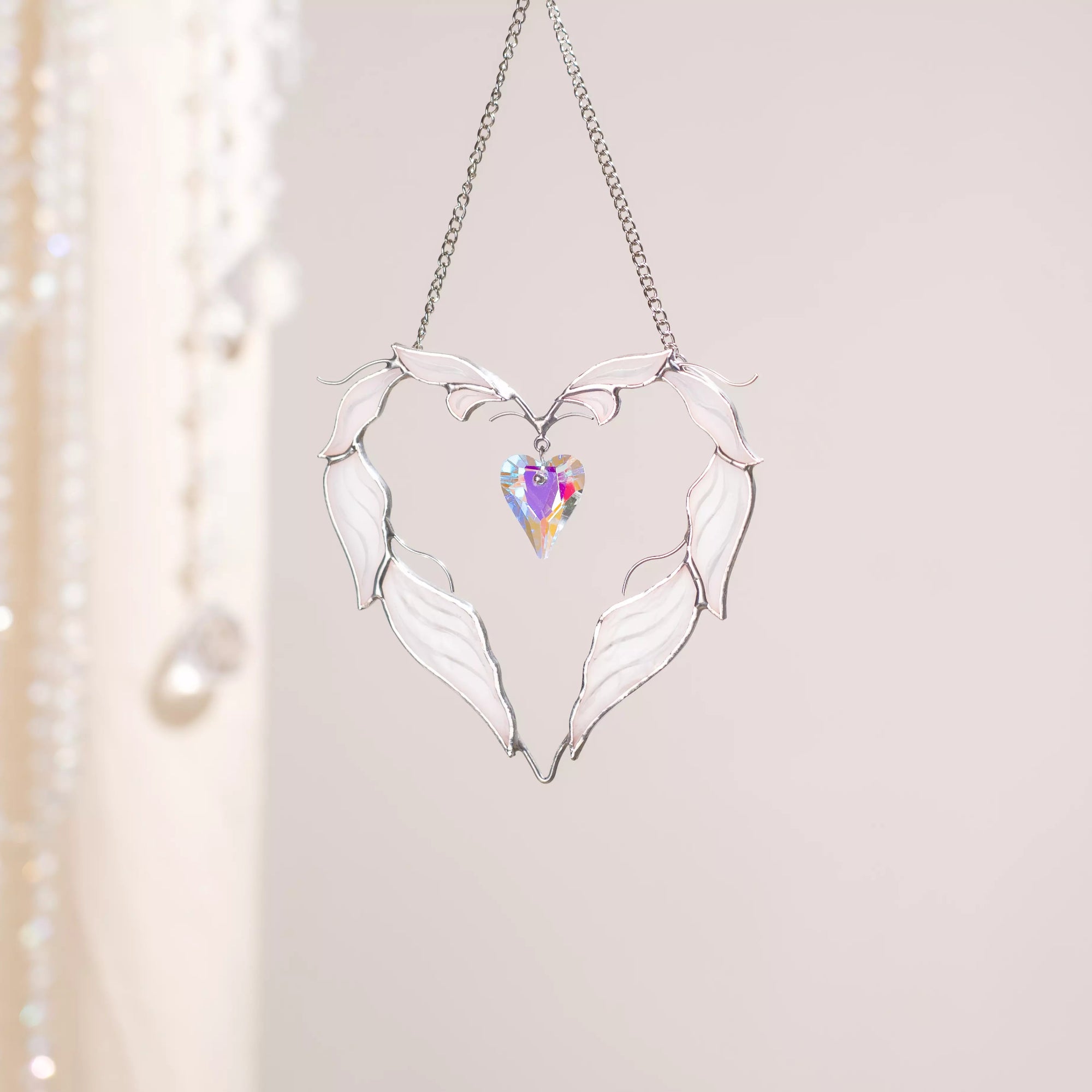 Winged heart stained glass suncatcher hanging on a chain in a calm interior setting.