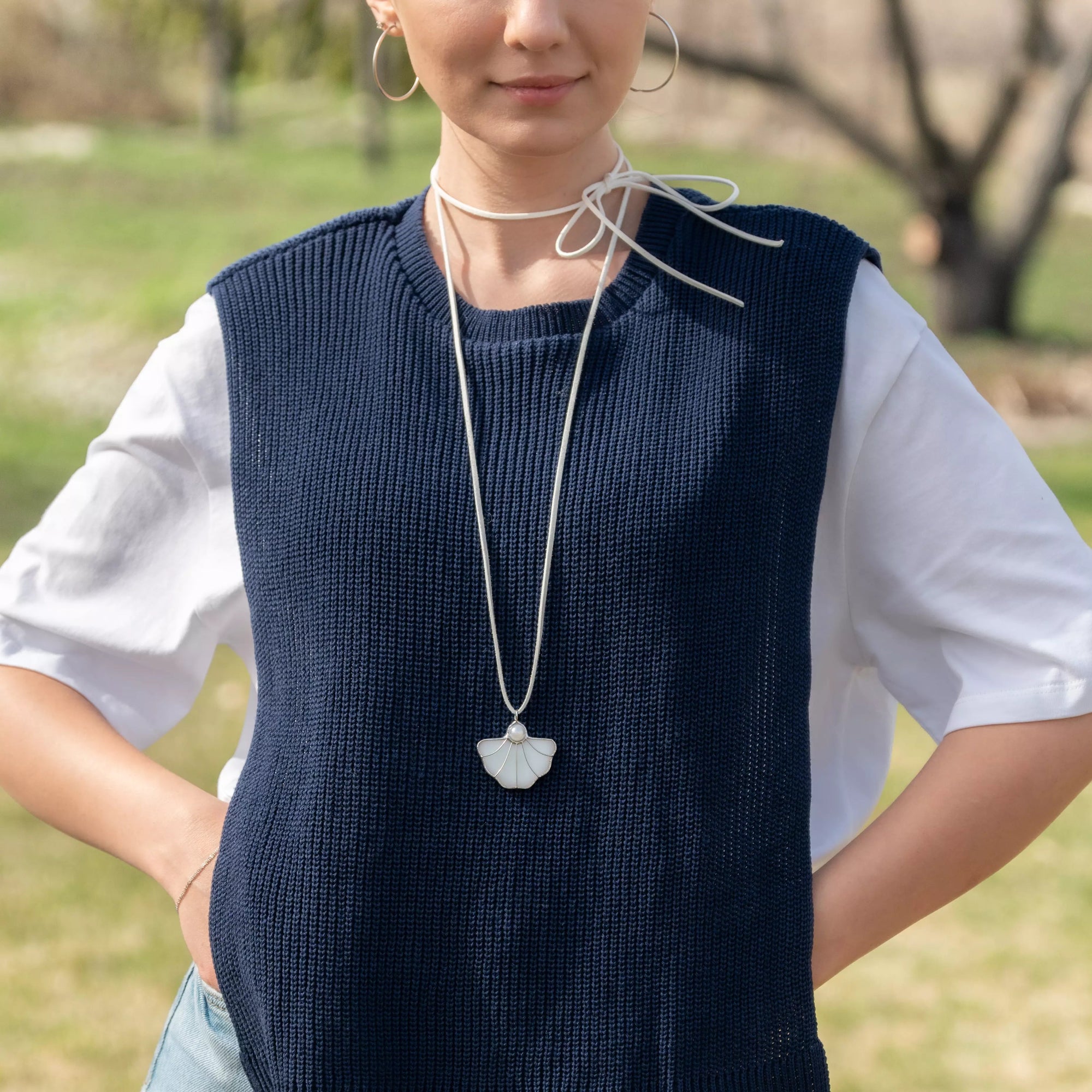 Minimal white shell pendant on a long white cord, styled with casual layered outfit – comfortable and chic necklace for daily wear.