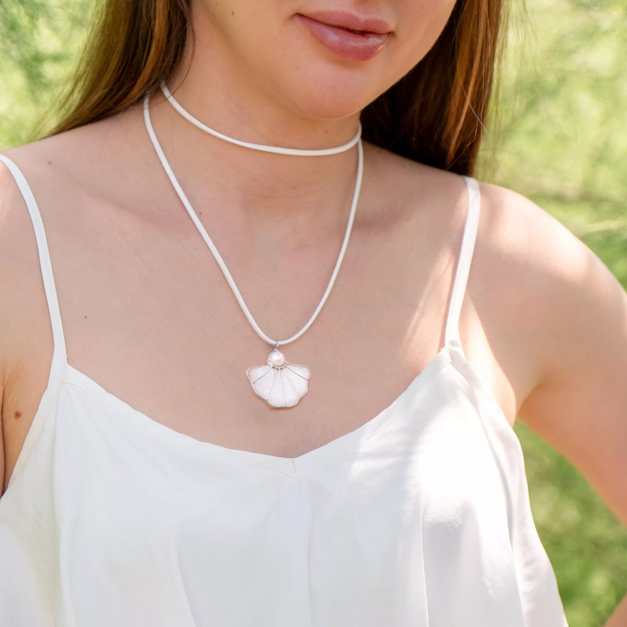 Handcrafted white shell-shaped pendant on vegan suede cord, styled with a summer dress – fresh, bright and gift-ready for any occasion.