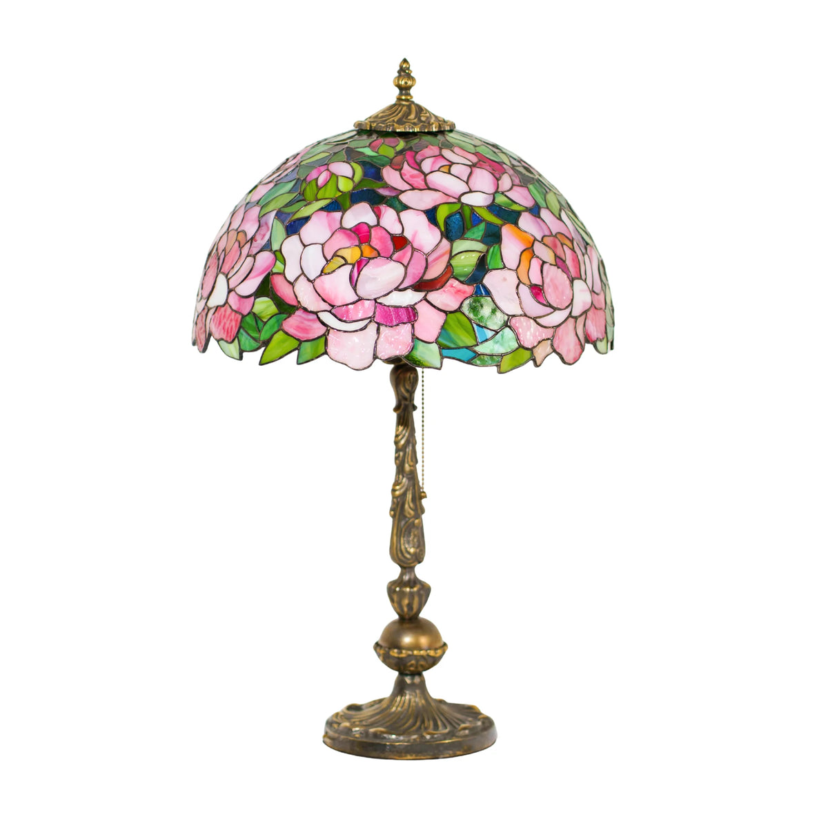 Stained glass peony table lamp glowing softly with colorful light reflections in a dark room, pink and green glass petals catching the warm bulb light - a handmade Tiffany style lamp for cozy spaces