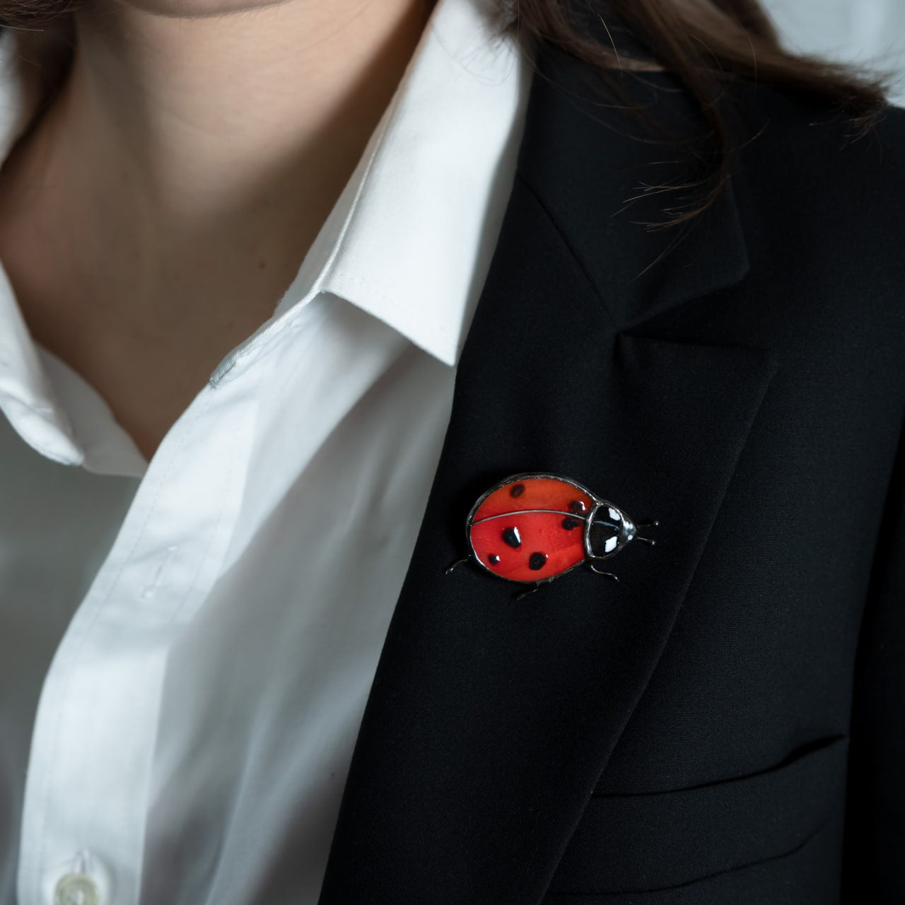 Stained glass brooch red ladybug on a black blazer