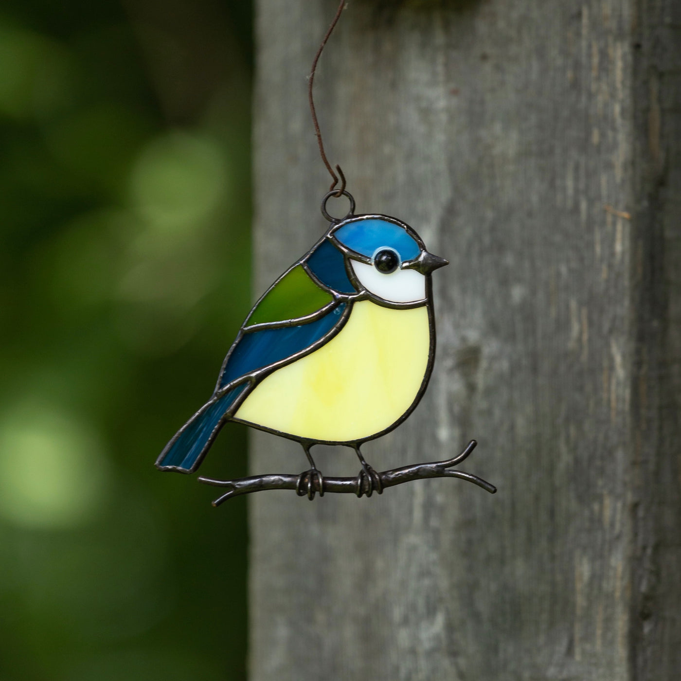 Stained glass blue chickadee sitting on the branch