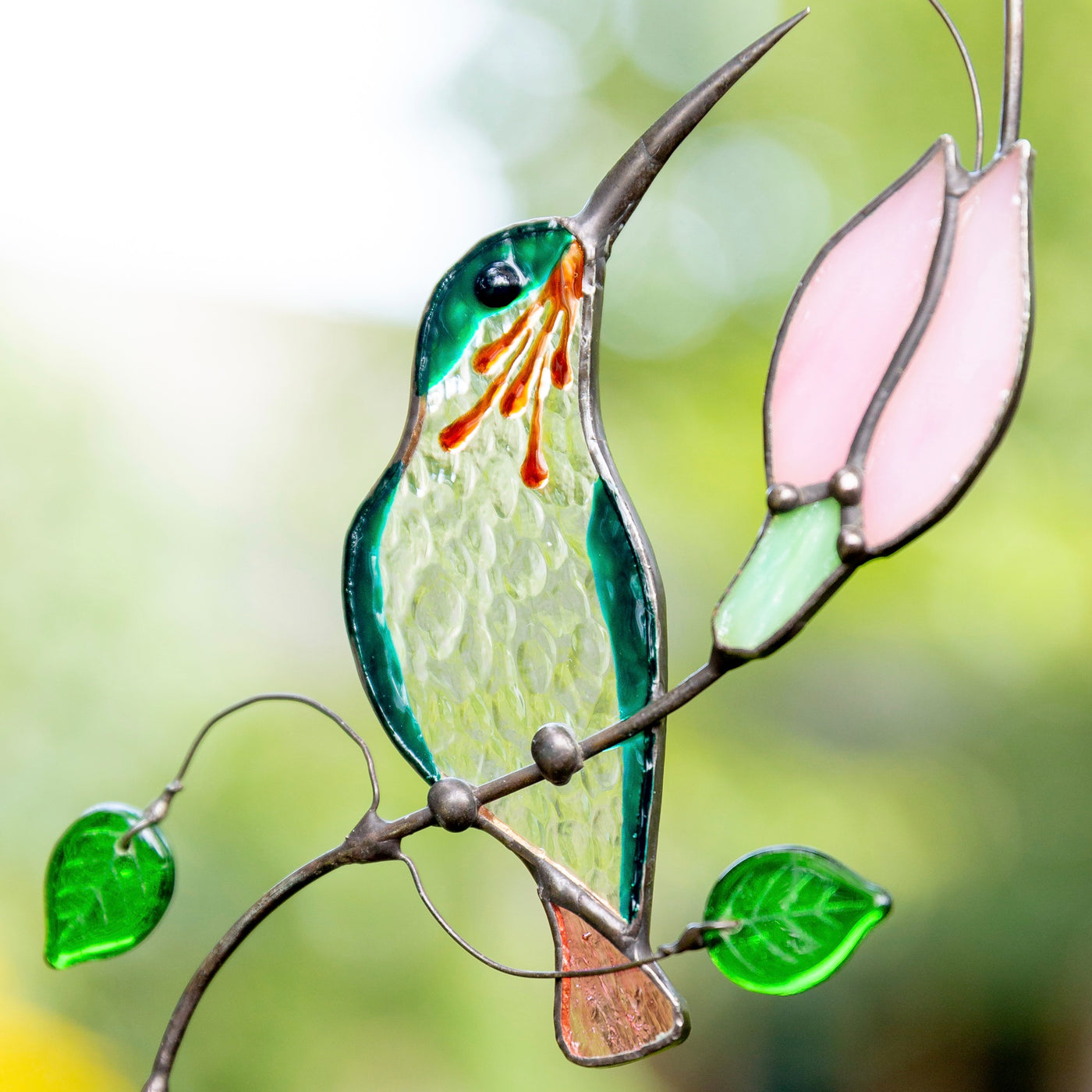 Stained glass zoomed hummingbird on the branch with pink flower