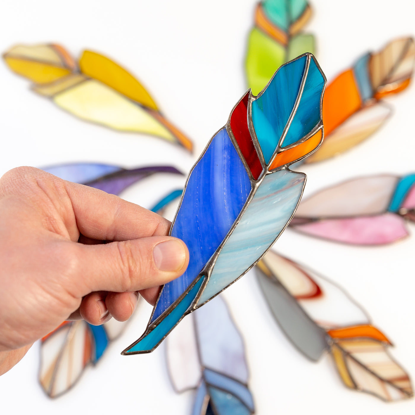 Blue stained glass feather with red and orange parts window hanghing