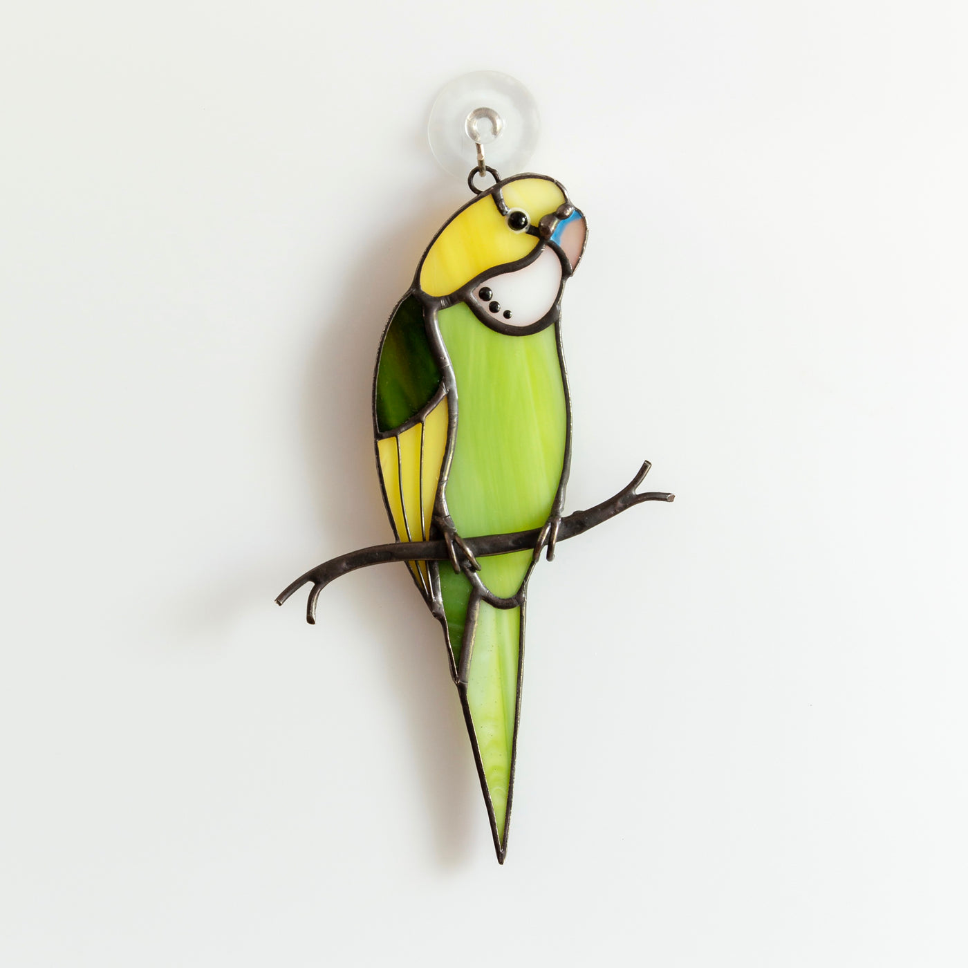 Green budgerigar sitting on the branch stained glass window hanging