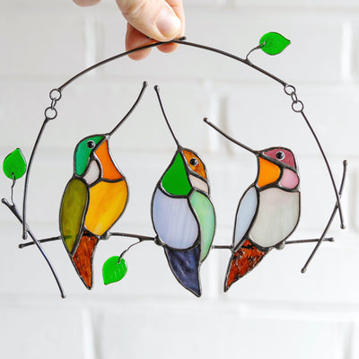 Suncatcher of three stained glass hummingbirds on the horizontal branch 