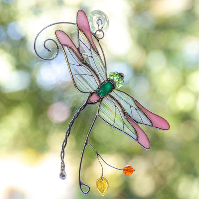 Stained glass pink dragonfly sitting on the branch window hanging 