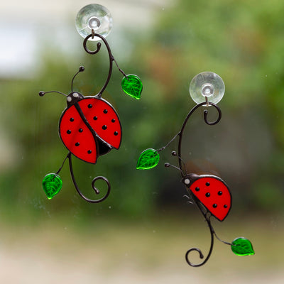 A pair of stained glass ladybugs on the branch with leaves window hanging