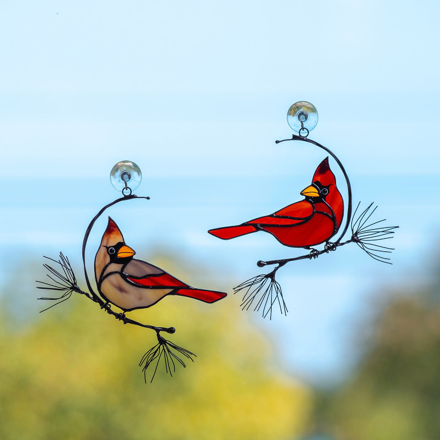 A pair of stained glass male and female winter redbirds suncatchers