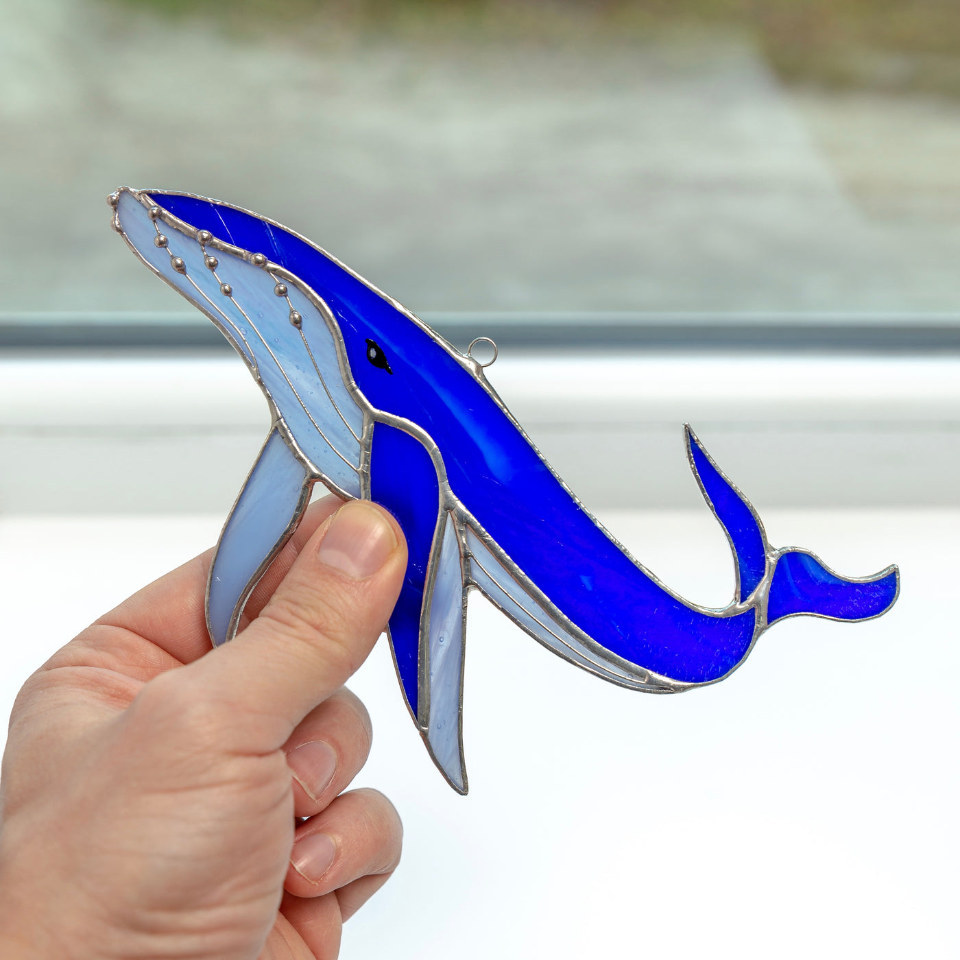 Stained glass whale window hanging of a royal blue colour with sky-blue lower part