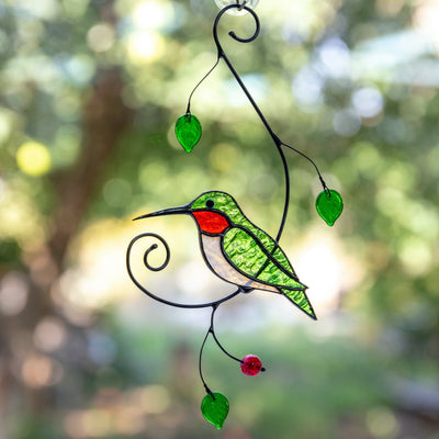 Green hummingbird sitting on the branch with leaves and berries suncatcher of stained glass