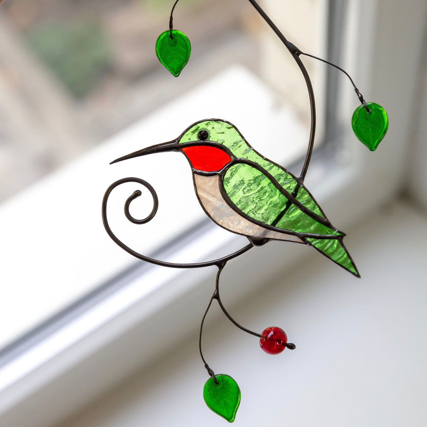Zoomed stained glass green hummingbird on the branch window hanging
