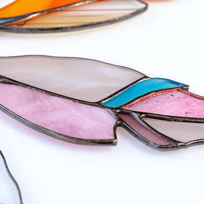 Zoomed stained glass pink feather with a blue part suncatcher