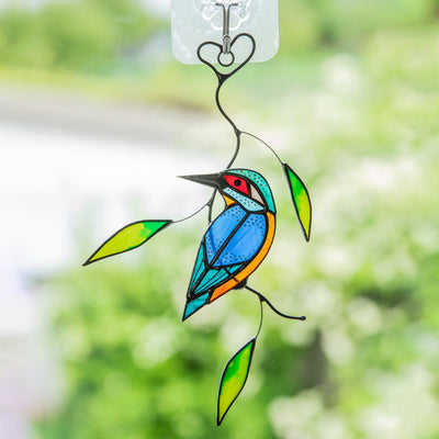 Stained glass kingfisher sitting on the branch with leaves suncatcher
