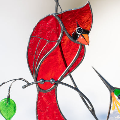 Close-up of stained glass cardinal with vibrant red glass and black detailing.