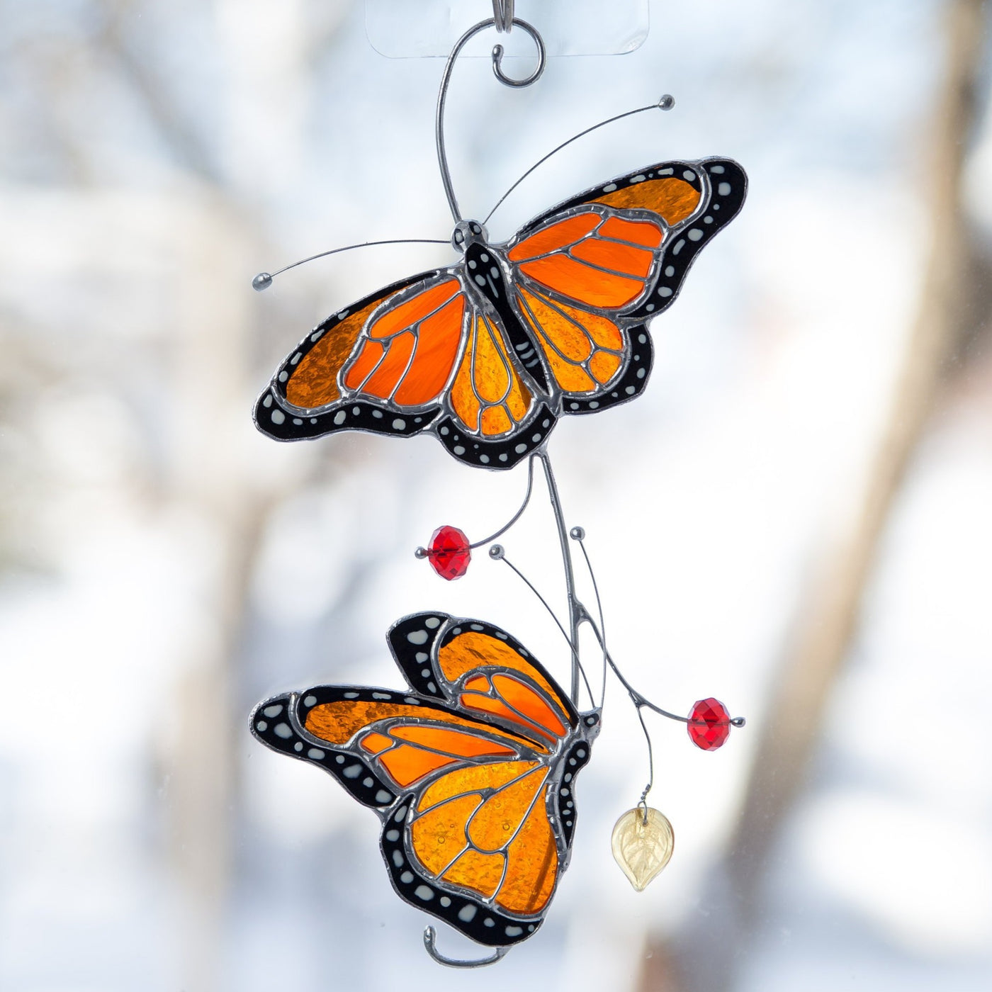 Close-up of orange stained glass monarch butterflies with sunlight highlighting their colors.