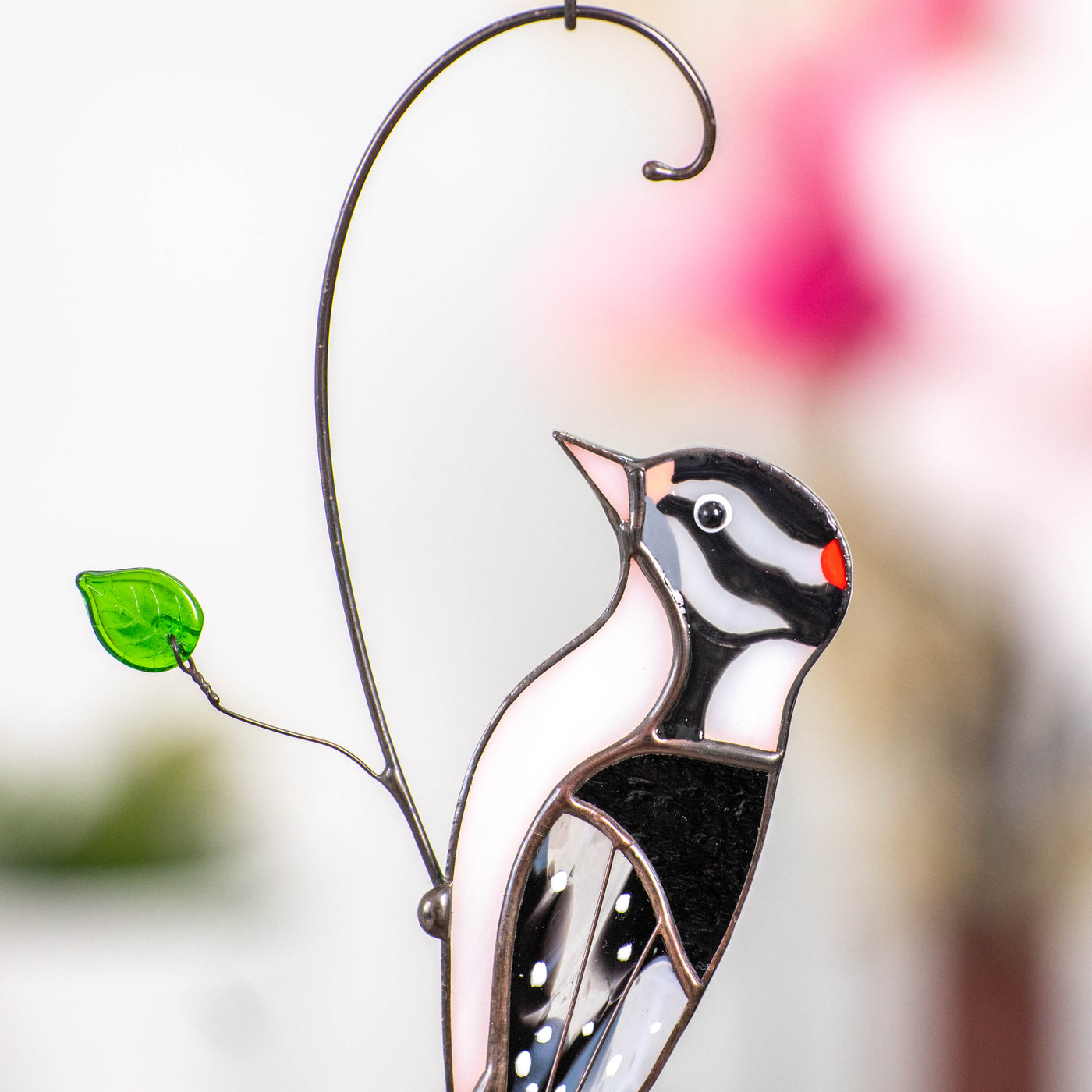 Zoomed-in view of a stained glass woodpecker showing red, black, and white glass and green glass leaf detail.