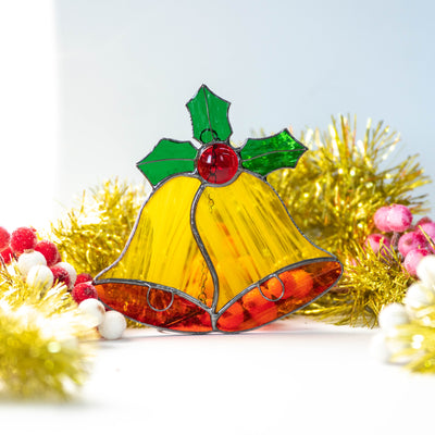 Bright yellow christmas bells with holly leaves on top suncatcher of stained glass