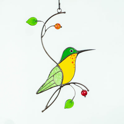 Green hummingbird with yellow belly sitting on the branch suncatcher of stained glass