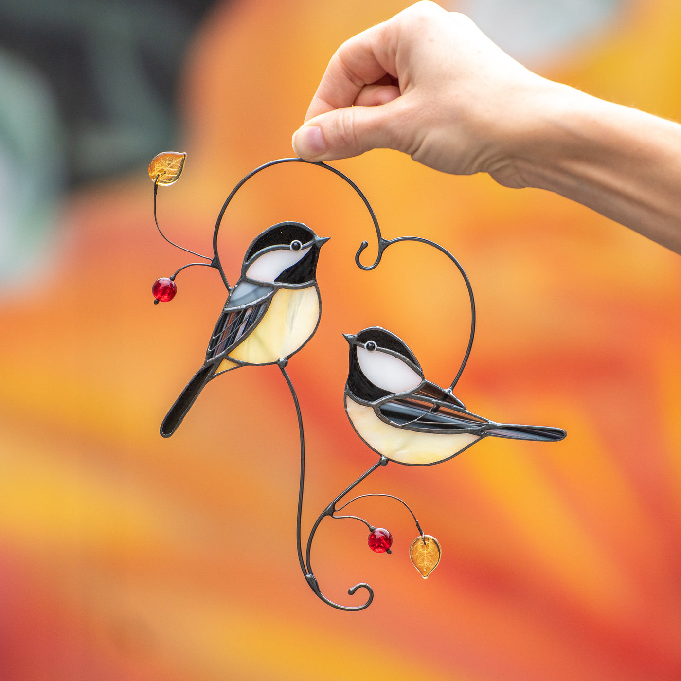 Couple of chickadees sitting on the branch in the shape of heart suncatcher of stained glass