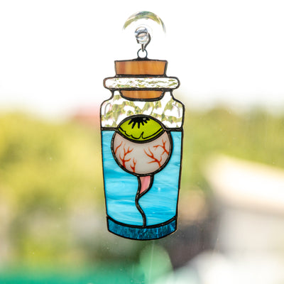 Stained glass suncatcher of torn out eye in the bottle 