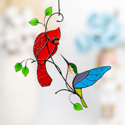 Stained glass red cardinal looking at multicolour hummingbird suncatcher