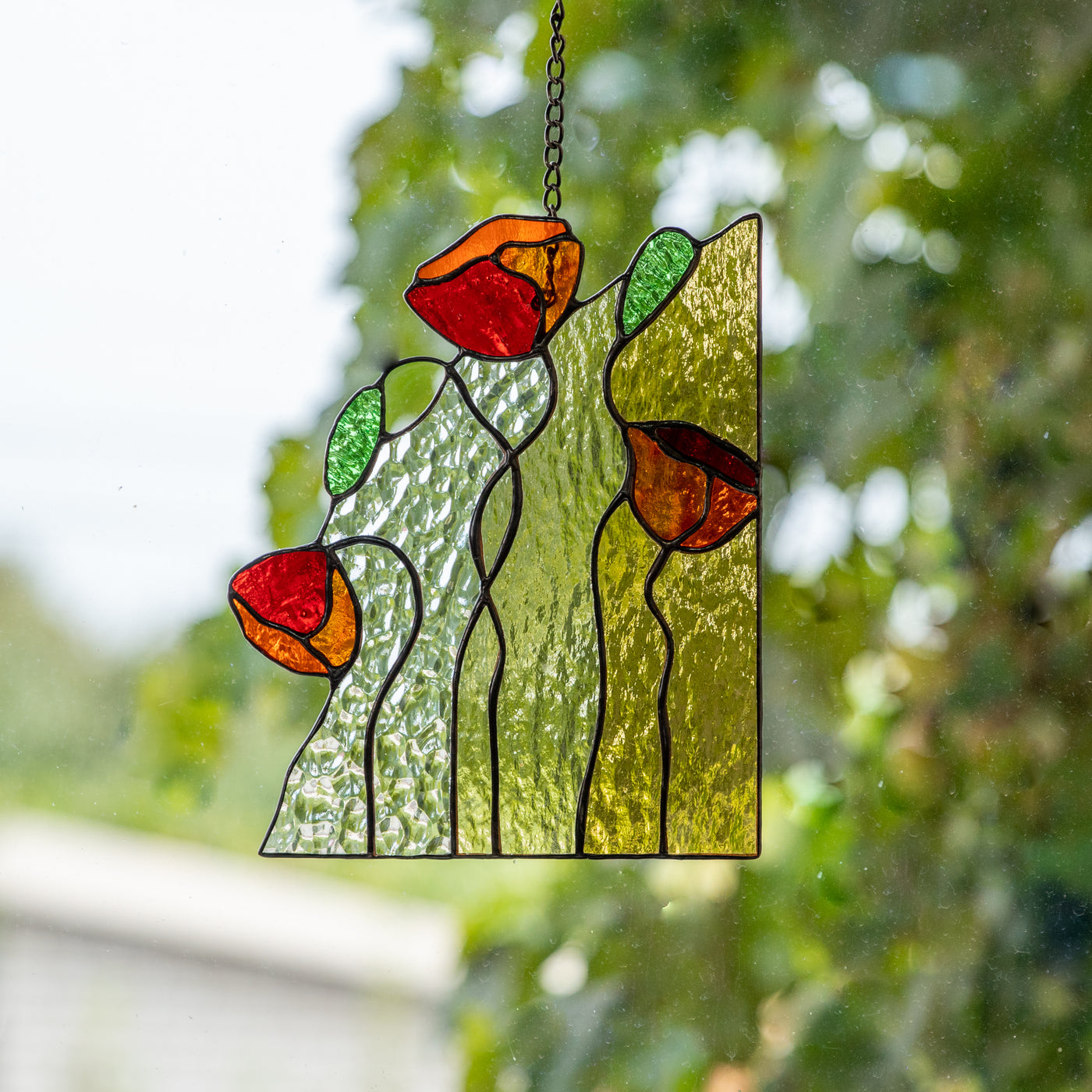 Window panel of stained glass depicting three red poppies