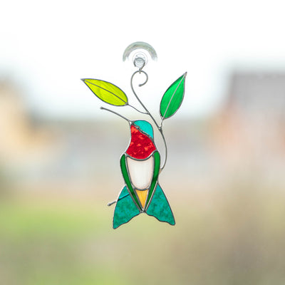 Stained glass ruby-throated hummingbird sitting on the branch with leaves suncatcher