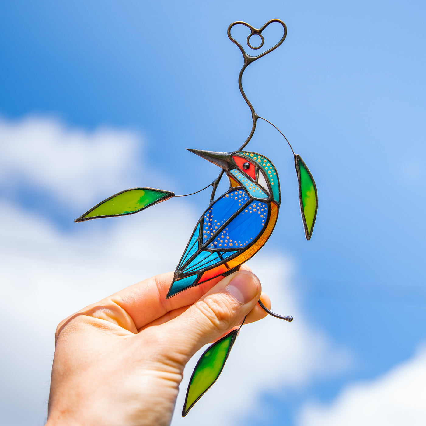 Suncatcher of a stained glass bright kingfisher with green leaves
