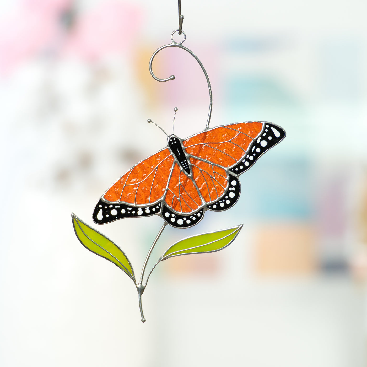 Stained glass window hanging of a monarch butterfly with two green leaves