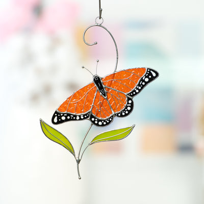 Stained glass window hanging of a monarch butterfly with two green leaves