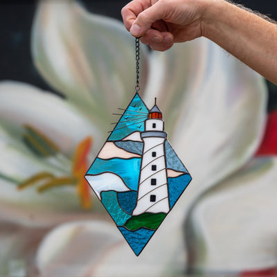 Stained glass rhombus panel with lighthouse in the waters on it