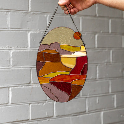 An oval panel of stained glass depicting Arizona Grand Canyon