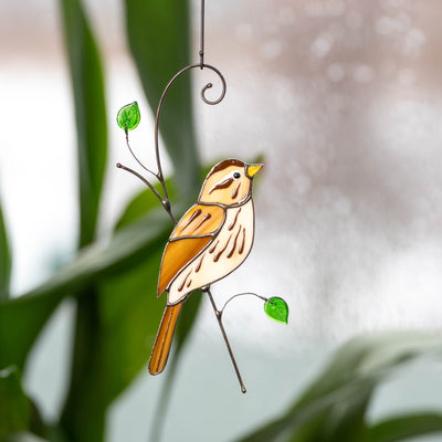 Stained glass sparrow sitting on the branch with green leaves suncatcher