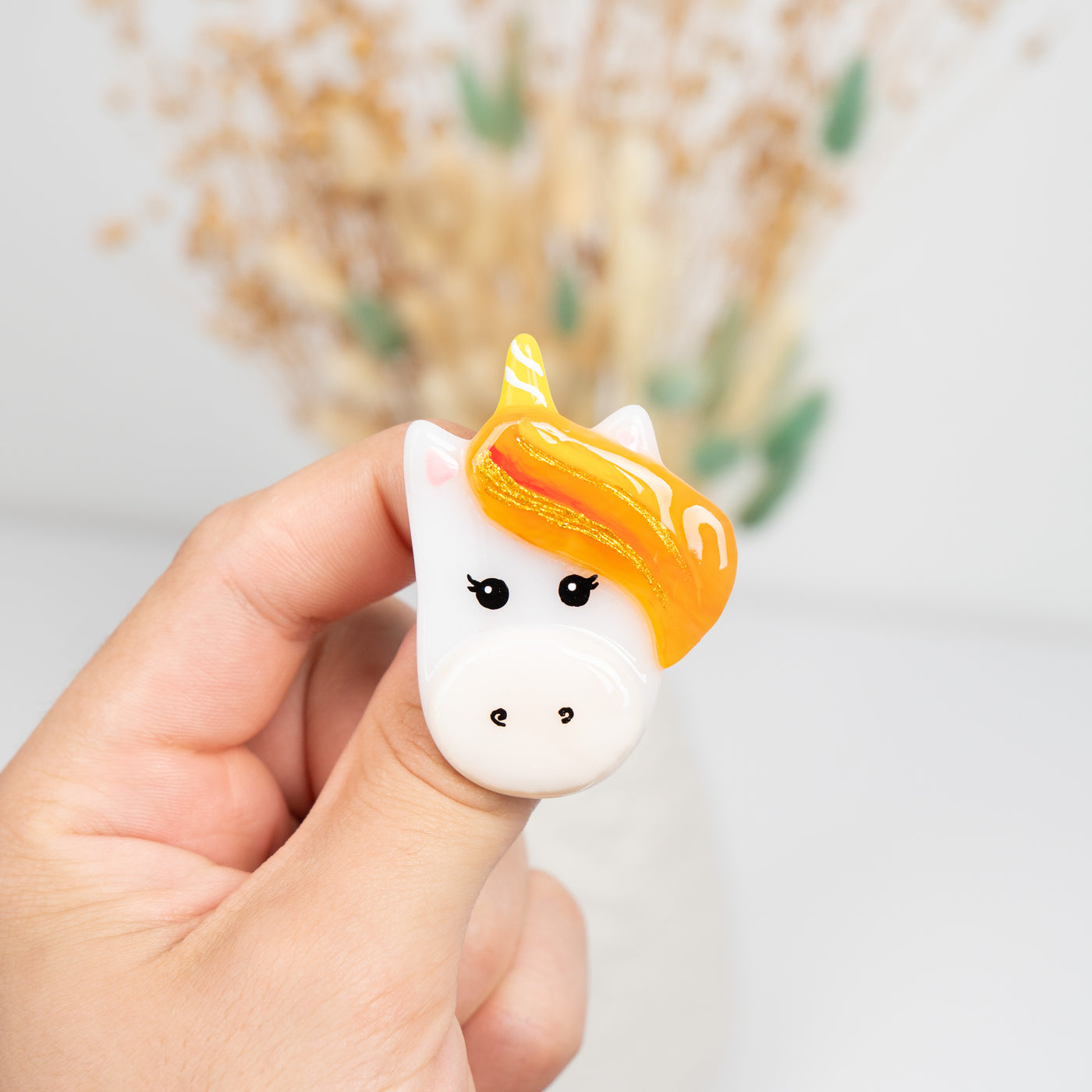 Stained glass brooch of a white unicorn with orange mane 