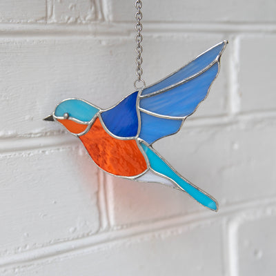 Stained glass suncatcher of a flying bluebird