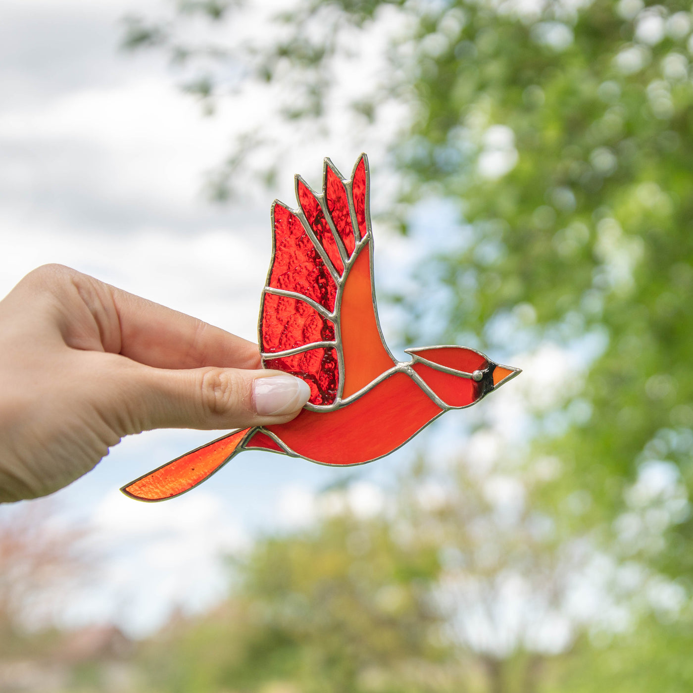 Stained glass suncatcher of flying male cardinal 