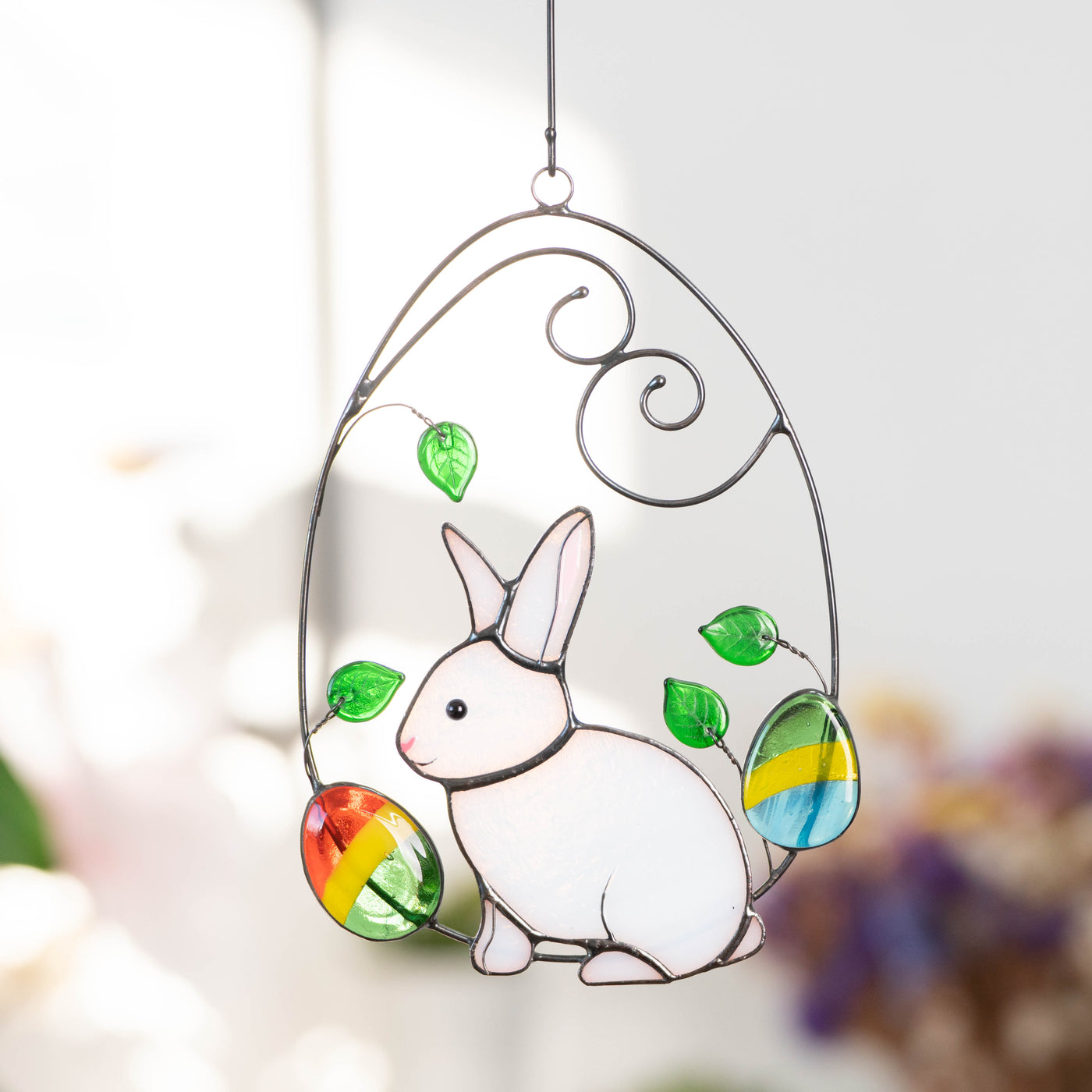Stained glass window hanging of bunny in a wired egg with two eggs on each side for Easter 