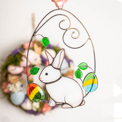 Stained glass bunny in a wired egg with two eggs on each side window hanging for Easter celebrations