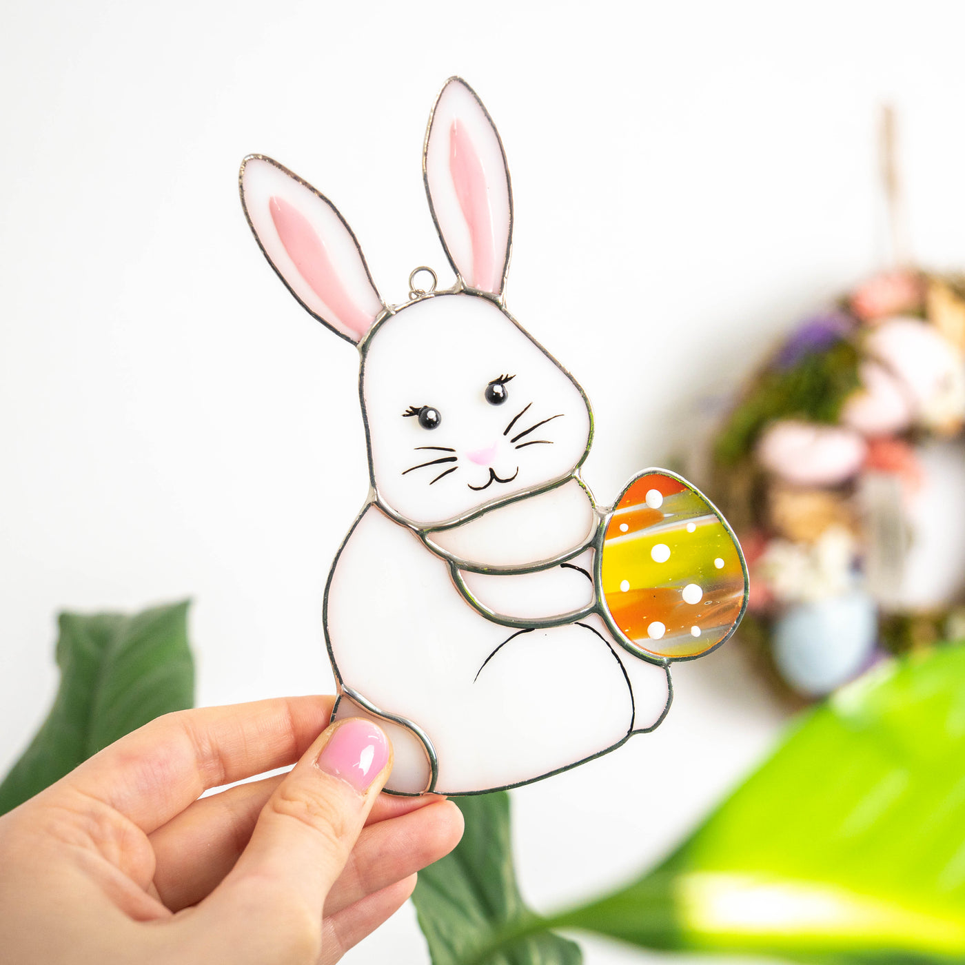 Stained glass suncatcher of Easter bunny with an orange egg 